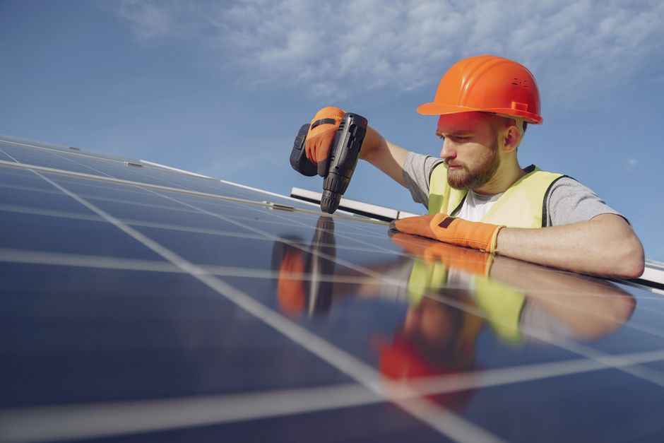 Professional solar panel installer working carefully on a residential roof